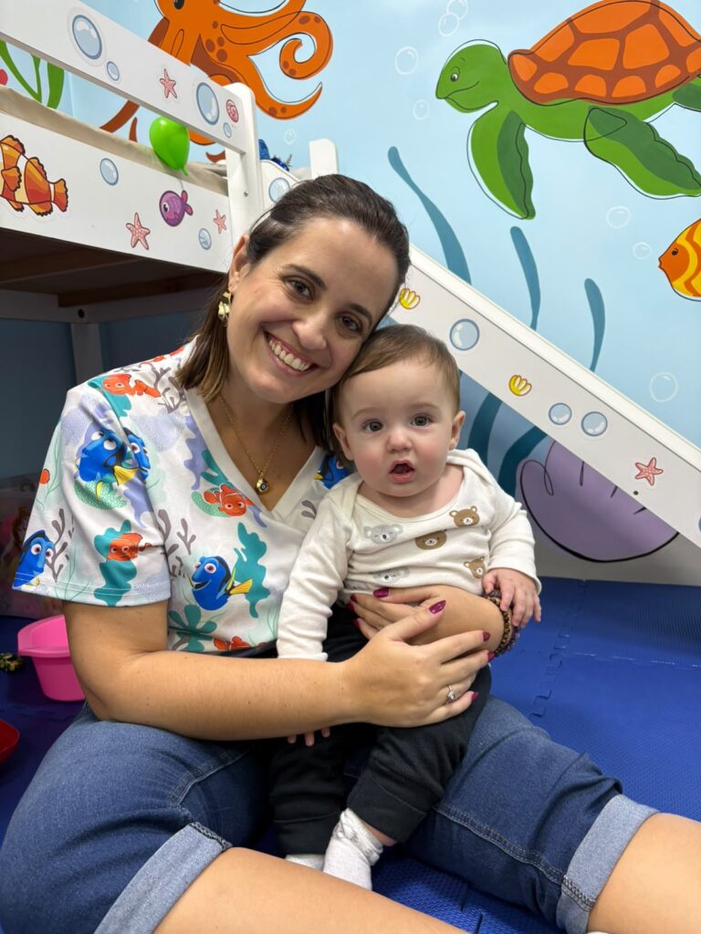 Dra. Patty Terrível sentada no tatame com bebê na consulta de puericultura