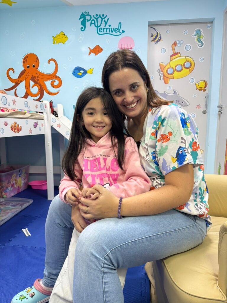 Dra. Patty Terrível com paciente no colo na poltrona do consultório
