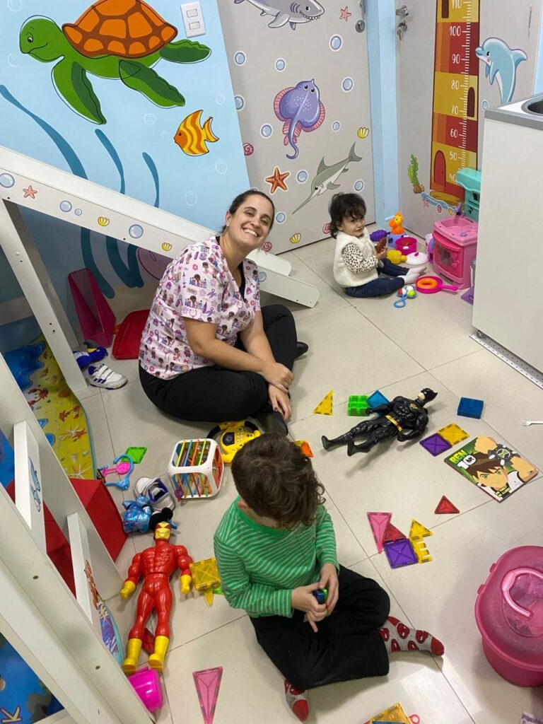 Dra. Patty Terrível brincando com crianças no chão da sala de atendimento